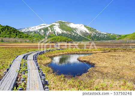 The confessing mountain of the remaining snow reflected in the pond weir 53750248