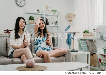 friends holding ice beer on couch watching movie 53754053