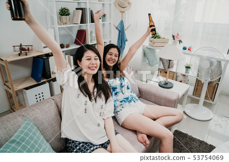 women watching TV raise hands up with ice beer women watching TV raise hands up with ice beer 53754069