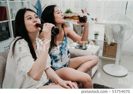 two friends having fun with bottles of drink two friends having fun with bottles of drink 53754070