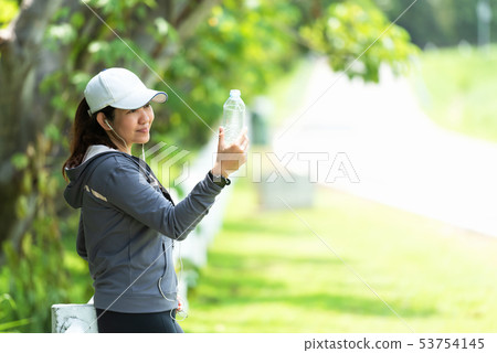Healthy athletic asian woman is drinking pure wate 53754145