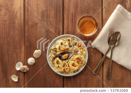 Seafood pasta. Tagliolini with mussels, shrimps, clams and squid rings, with a glass of white wine Seafood pasta. Tagliolini with mussels, shrimps, clams and squid rings, with a glass of white wine 53761089