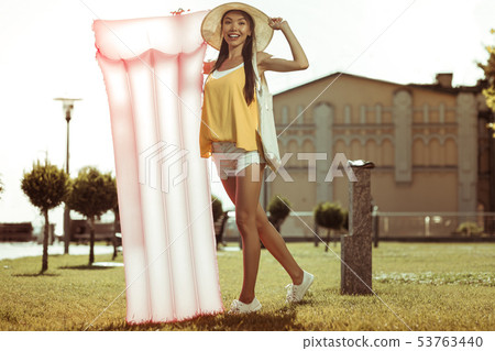 Bewitching beauty standing with a pink inflatable air mattress outdoors Bewitching beauty standing with a pink inflatable air mattress outdoors 53763440
