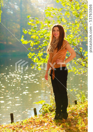 Woman walking through park in fall Woman walking through park in fall 53763866
