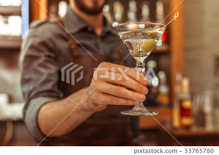 Close-up photo of bar worker holding a martini cocktail 53765780