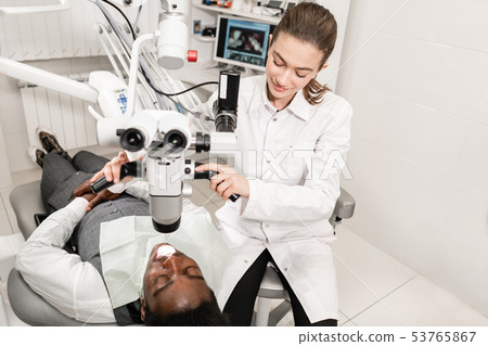 Female dentist advanced user, dental tools. Setup microscope for examining his patients teeth. in Female dentist advanced user, dental tools. Setup microscope for examining his patients teeth. in 53765867