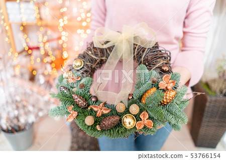 Beautiful festive wreath of fresh spruce with ball toys in woman hands. Christmas mood. Bokeh of Beautiful festive wreath of fresh spruce with ball toys in woman hands. Christmas mood. Bokeh of 53766154