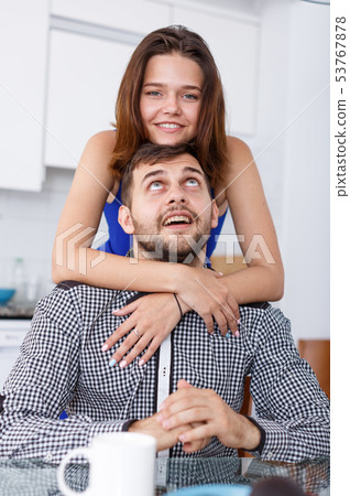 Smiling couple sitting at kitchen table and drinking tea at home 53767878