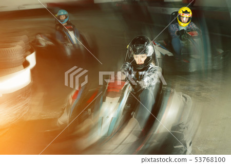 Group of male and females driving racing cars Group of male and females driving racing cars 53768100