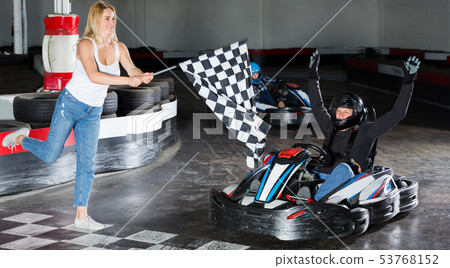 Young woman with race flag and man driving car Young woman with race flag and man driving car 53768152