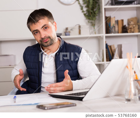 Young man with laptop and papers working in office 53768160