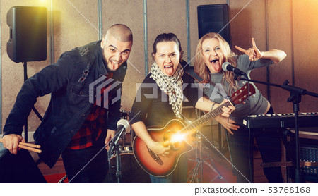 Three bandmates posing together with musical instruments in rehe 53768168