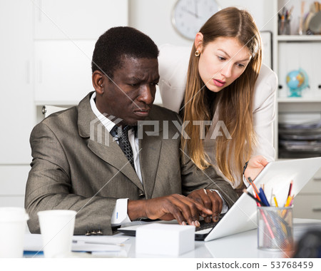 Young female manager helping to male colleague with new project at laptop Young female manager helping to male colleague with new project at laptop 53768459