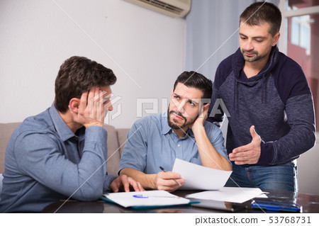 Three upset males with papers at table Three upset males with papers at table 53768731