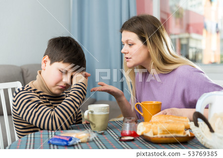 Upset mother and unhappy son arguing during breakfast indoors Upset mother and unhappy son arguing during breakfast indoors 53769385