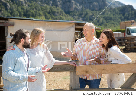 Friends chatting near wooden fencing Friends chatting near wooden fencing 53769461