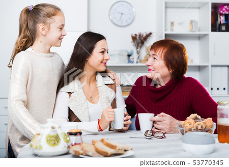 Senior woman with family drinking tea at home Senior woman with family drinking tea at home 53770345