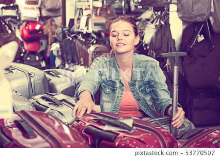 happy teenager girl choosing new large plastic luggage bag happy teenager girl choosing new large plastic luggage bag 53770507