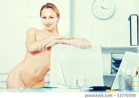Young nude woman standing near the table and posing in the office 53770508