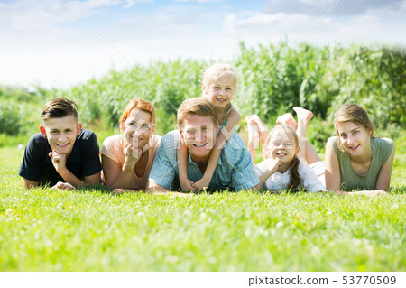 Glad man and woman with four kids lying in park Glad man and woman with four kids lying in park 53770509