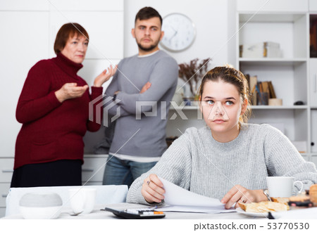 Distressed girl with paperwork and irritated family behind 53770530