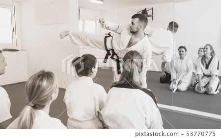 Beardy smiling coach is showing new martial moves to adults 53770775