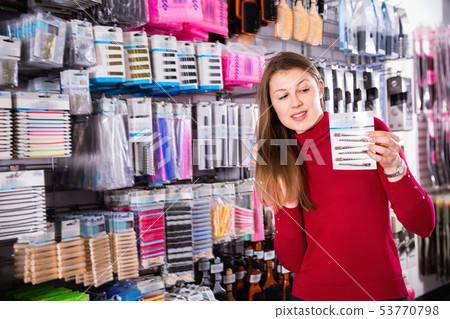 Young woman is choosing new hair clips in hair care store. Young woman is choosing new hair clips in hair care store. 53770798