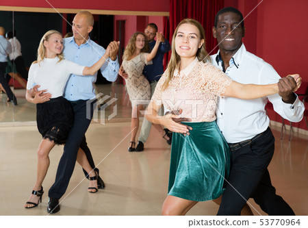 Positive adult pairs enjoying dancing salsa in modern dance studio 53770964
