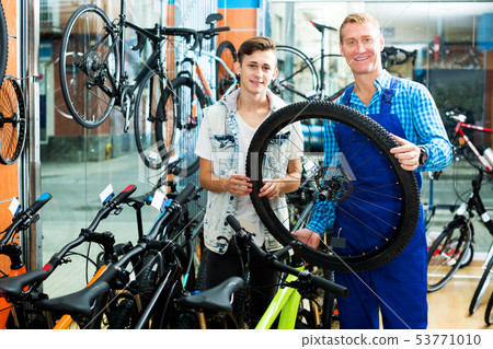 Man working with bicycles wheel and helping boy 53771010
