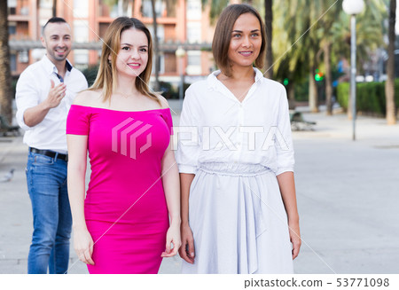 Young women are walking and stranger man is want acquaintance with them 53771098