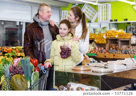 Parents and girl with purchases in trolley in fruit market Parents and girl with purchases in trolley in fruit market 53771126