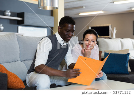 Adult woman with her husband are holding folder with prices for furniture 53771132
