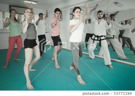 adults attempting to master new moves during karate class 53771194