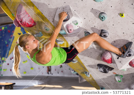 Woman training at bouldering gym 53771321
