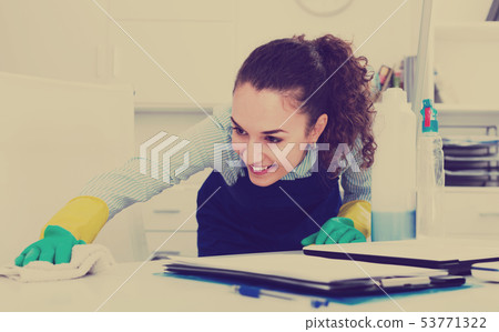 Glad woman in uniform cleaning in office 53771322