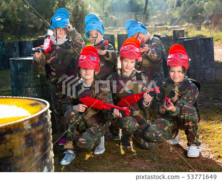 Friendly group of children paintball players in camouflage posing with guns on paintball playing field outdoors Friendly group of children paintball players in camouflage posing with guns on paintball playing field outdoors 53771649