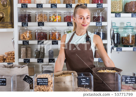 Portrait of girl seller who is standing near showcase with nuts 53771799