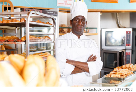 Proud baker in white uniform behind counter 53772003