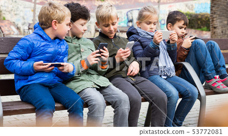 Five kidsare chatting on their smartphone Five kidsare chatting on their smartphone 53772081