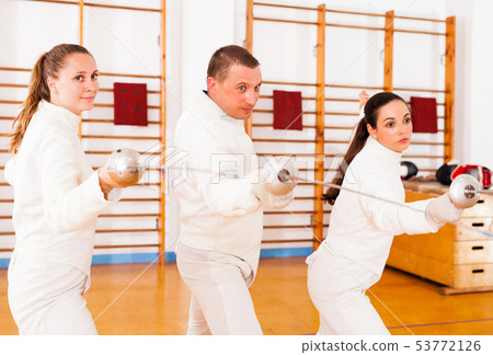 Man and women fencers practicing movements together Man and women fencers practicing movements together 53772126