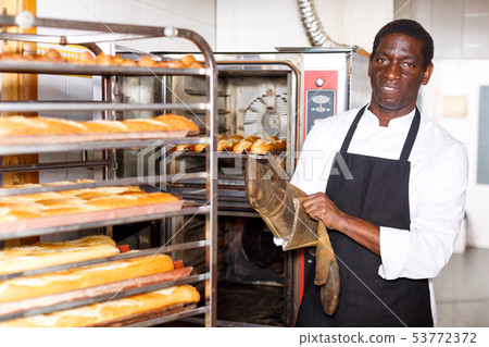 Baker putting on heat resistant gloves Baker putting on heat resistant gloves 53772372