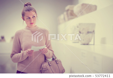Young woman with guidebook looking at sculptures Young woman with guidebook looking at sculptures 53772411