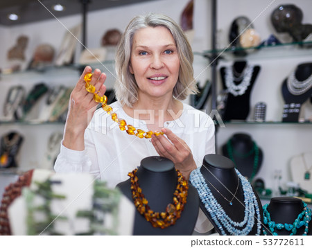 Woman trying on a aventurine necklace and earrings at a jewelry store 53772611