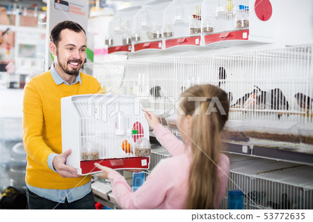 Male store assistant offering cage with canary bird Male store assistant offering cage with canary bird 53772635