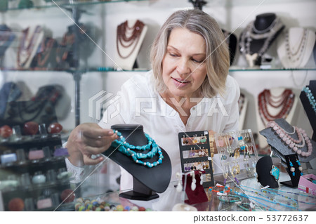 Seller of jewelry store lays the necklaces on the showcase Seller of jewelry store lays the necklaces on the showcase 53772637