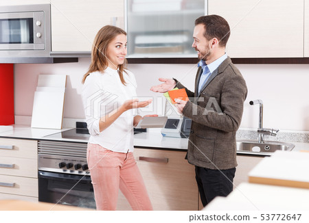 Smiling woman with her husband discussing in salon of appliances and materials Smiling woman with her husband discussing in salon of appliances and materials 53772647