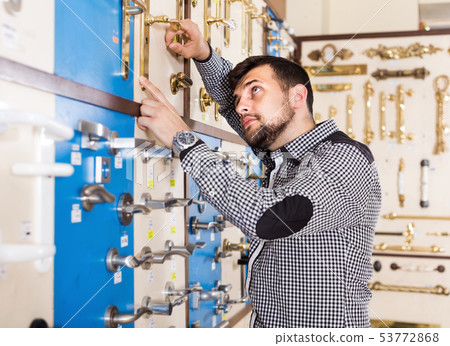 Young man deciding on best door handle 53772868