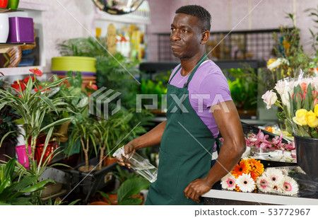 Man in apron posing in floral shop Man in apron posing in floral shop 53772967
