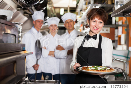 Smiling waitress with pizza in restaurant kitchen 53773394