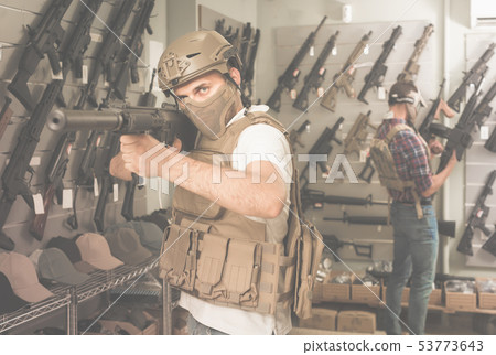 Young guys in military equipment with rifle in airsoft shop 53773643
